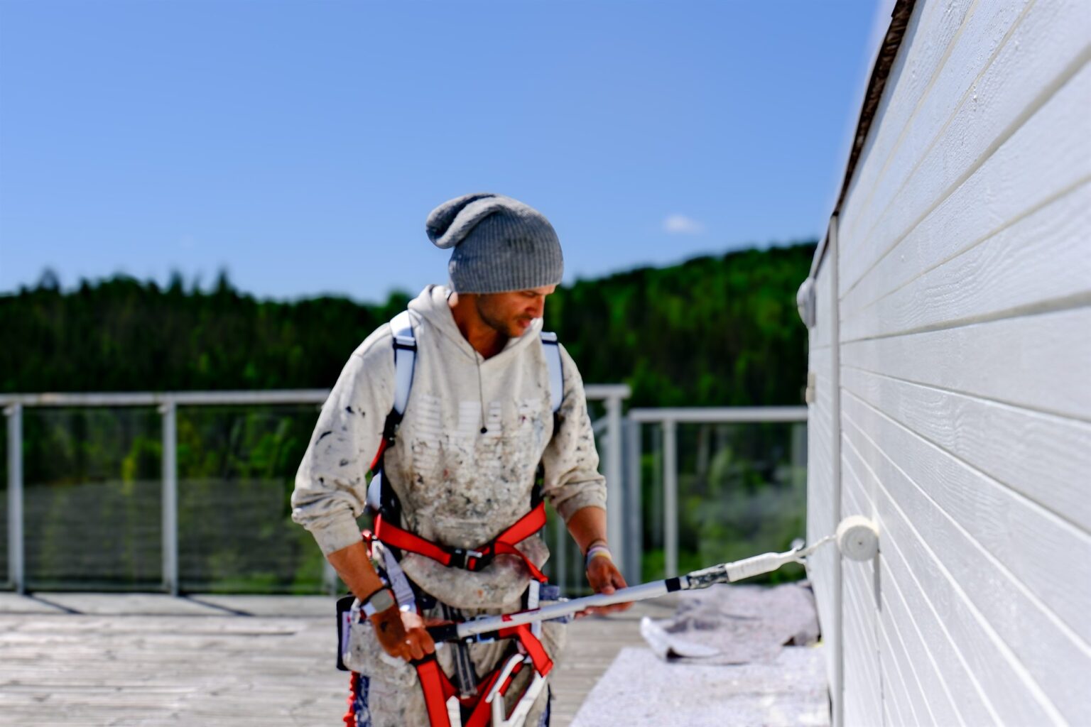 Maler på balkong under maling av trekledning